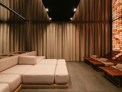 Modernes, gemütliches Lounge mit hellen Sofas und beleuchtetem Wandmosaik in warmen Tönen.