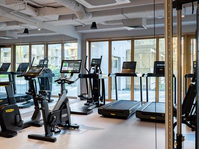 Moderner Fitnessraum mit Laufbändern, Heimtrainern und großen Fenstern mit Aussicht.