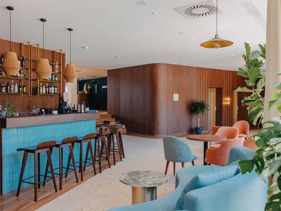 Modern eingerichtete Hotelbar mit blauen und orangen Sitzgelegenheiten und Holzakzenten.