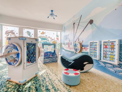 Area giochi per bambini a tema oceano con giochi interattivi in una stanza d'hotel.