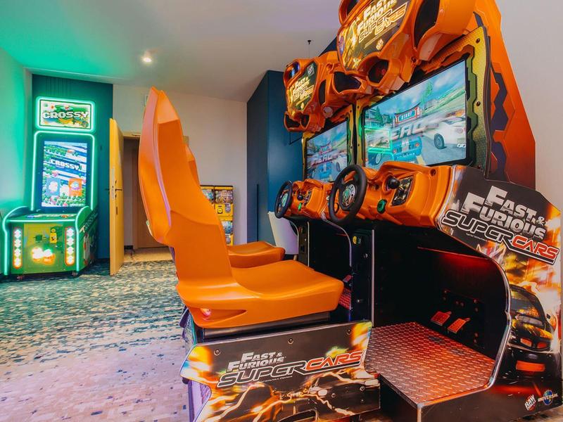 Slot machine con sedili arancioni in una sala giochi di un hotel.