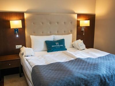 Modernes Hotelzimmer mit Doppelbett, gepolstertem Kopfteil, Nachttischen und Wandlampen