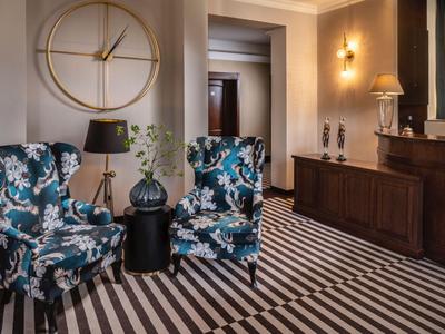 Gemütliche Sitzecke mit gemusterten Sesseln und Streifenboden in einem eleganten Hotelbereich.