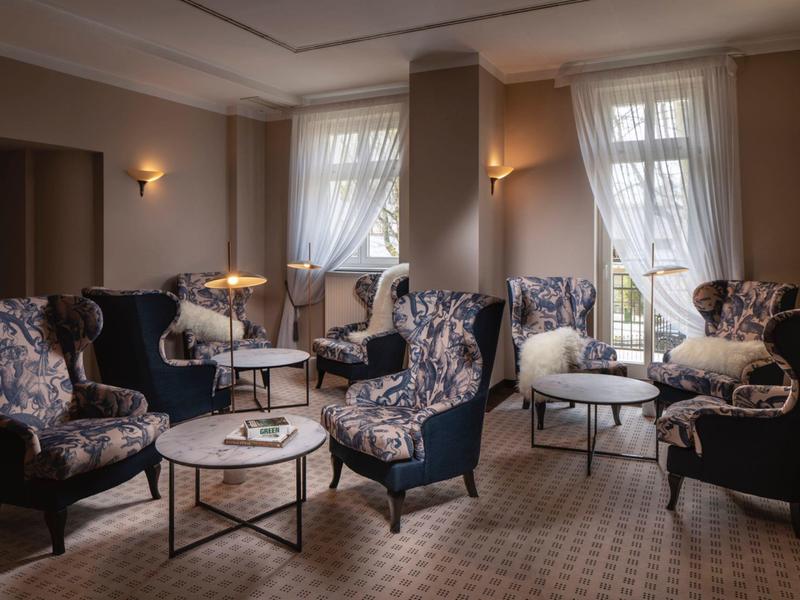 Obývací pokoj s elegantními křesly, stolky a tlumeným osvětlením v útulném hotelu.