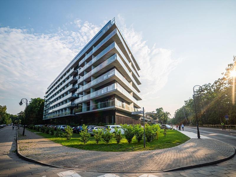 Edificio moderno su più piani all'angolo di una strada verde alla luce del sole.