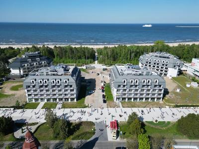 Mehrere moderne Apartmentgebäude nahe einem Sandstrand mit Blick auf das Meer.