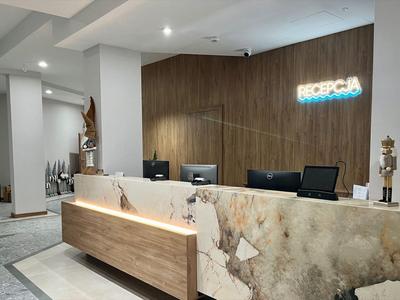 Moderner Hotel-Empfang mit Marmor- und Holzakzenten und beleuchtetem Schild an der Wand.