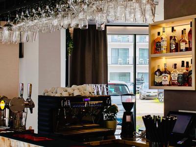 Moderne Bar mit Espressomaschine, Gläsern und Spirituosenregal in einem Café.