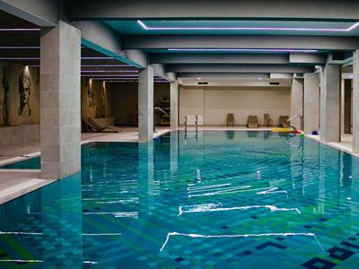 Piscina interna con acqua blu e colonne in un hotel moderno