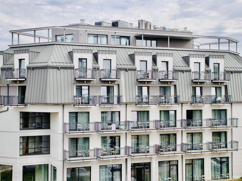 Edificio moderno di un hotel con balconi e tetto grigio sotto cielo nuvoloso.