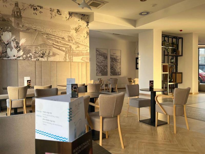 Area hotel o ristorante arredata modernamente con tavoli, sedie e decorazioni murali.