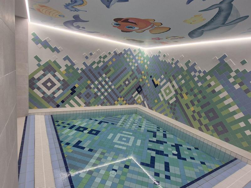 Piscina interna con motivo a mosaico digitale su pareti e soffitto con temi di acquario.