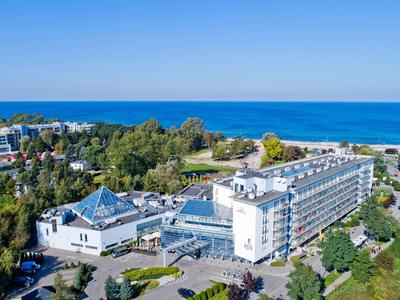 Großes Hotelgebäude an der Küste mit Blick auf das blaue Meer und umgeben von Bäumen.