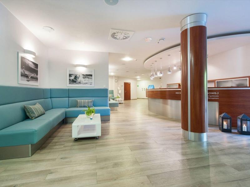 Nowoczesna lobby hotelowa z ławką, stołem, kolumną i recepcją na jasnej drewnianej podłodze.