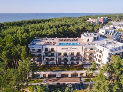 Ein Hotel mit Balkonen, umgeben von Wald und in Meeresnähe.