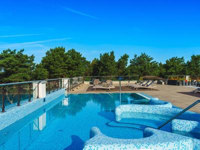 Piscine moderne avec espace sauna sur une terrasse avec vue sur les arbres et le ciel bleu