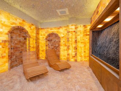 Entspannungsraum mit Salzwänden, zwei Holzliegen und Wasserfall im Spa-Bereich.