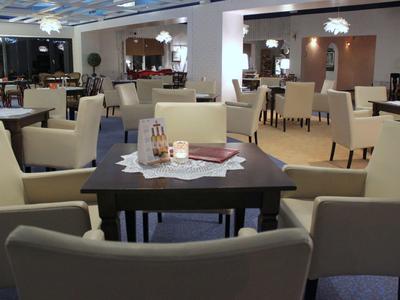 Moderní, světlý restauracní prostor s pohodlnými krémovými židlemi a tmavými dřevěnými stoly.