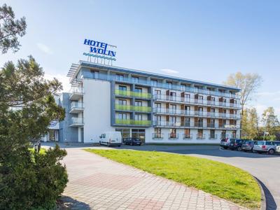 Modernes Hotelgebäude mit Balkonzimmern und Parkplätzen vor dem Haus an sonnigem Tag