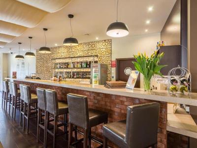 Moderne hotelbar met houten toonbank, leren stoelen en stijlvolle verlichting.