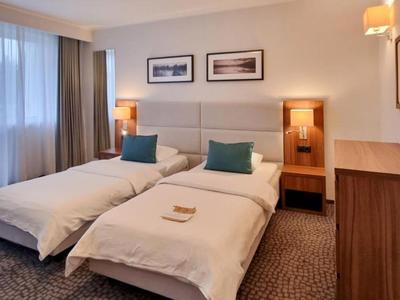 Moderne hotelkamer met twee eenpersoonsbedden, tapijt en zachte verlichting.