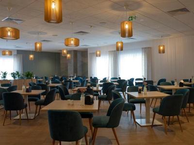 Modern ingerichte eetzaal met ronde meubels en warme plafondlampen.