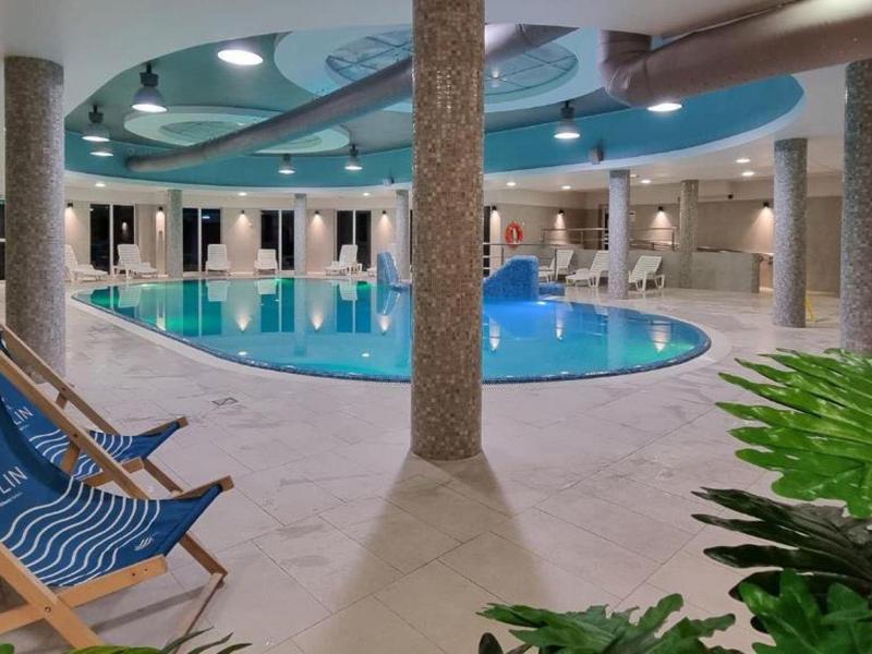 Innenpoolbereich mit Liegestühlen, Säulen und einer abgerundeten Decke in einem Hotel.