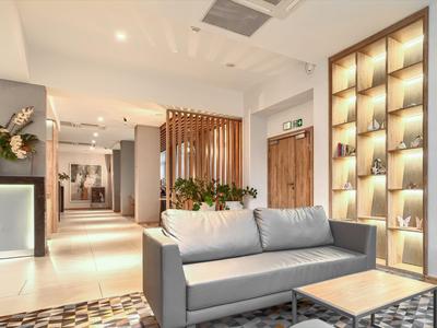 Moderne Hotellobby mit grauem Sofa, dekorativer Wand und indirekter Beleuchtung.