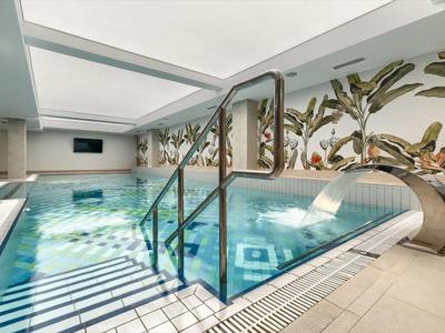 Moderner Innenpool mit Glasgeländer, Palmenwanddekor und entspannter Atmosphäre