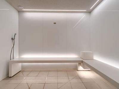 Modernes, weißes Saunarauminterieur mit minimalistischem Design und indirekter Beleuchtung.