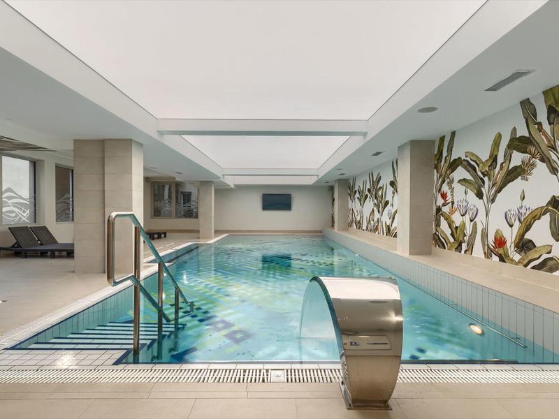 Innenpool mit moderner Einrichtung und tropischer Wandgestaltung in einem Hotel.