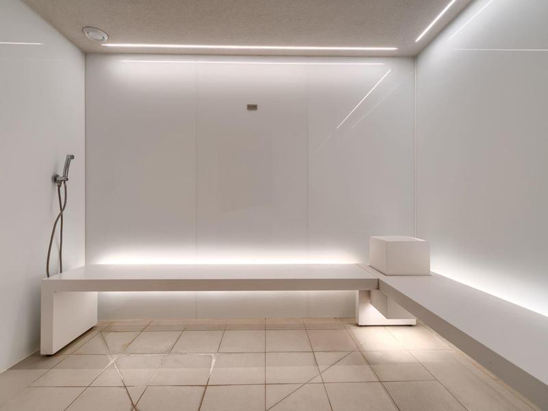 Modernes, weißes Saunarauminterieur mit minimalistischem Design und indirekter Beleuchtung.