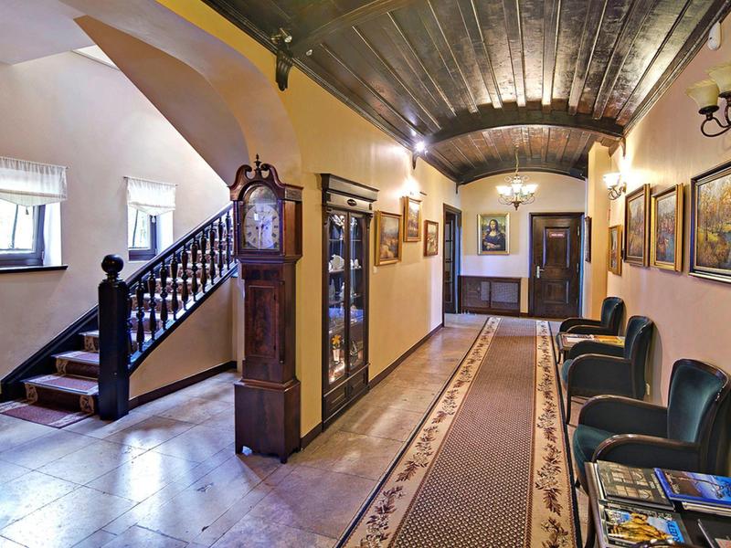 Przytulny korytarz z dywanem, skórzanymi fotelami, obrazami na ścianach i schodami w hotelu