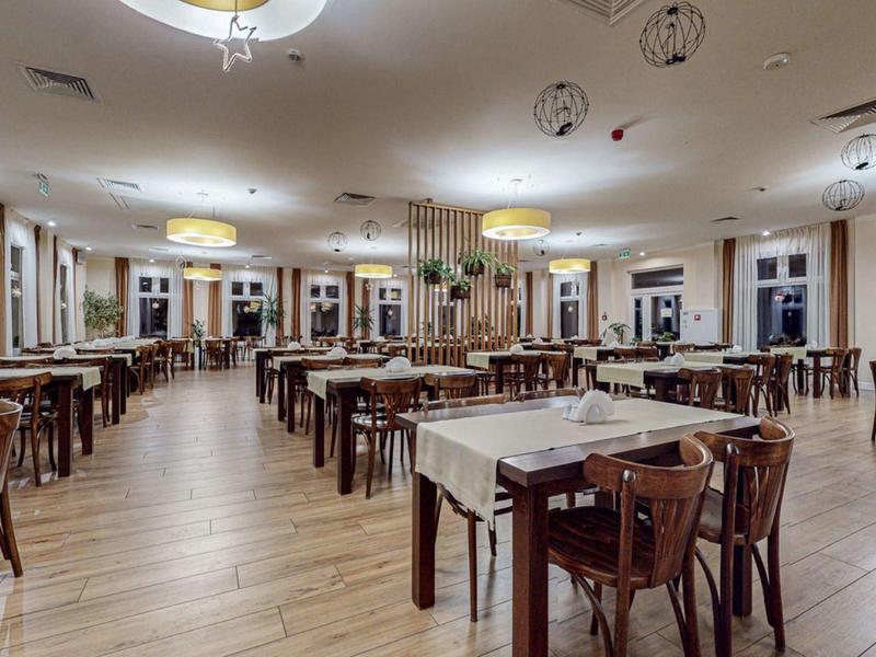 Duża, nowoczesna jadalnia z drewnianą podłogą i wieloma stołami oraz krzesłami.