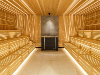 Sauna moderna con bancos de madera y luz cálida en un ambiente claro y acogedor.