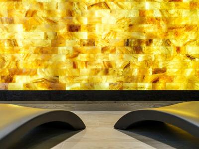 Dos tumbonas negras frente a una pared amarilla brillante en un área de spa.