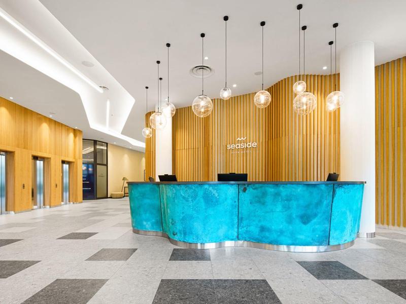 Recepción de hotel moderna con mostrador turquesa y paneles de madera