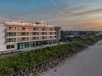 Modernes Hotelgebäude am Strand mit Blick auf das Meer bei Sonnenuntergang.