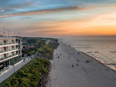 Plage au coucher du soleil avec hôtel et personnes au bord de l'eau