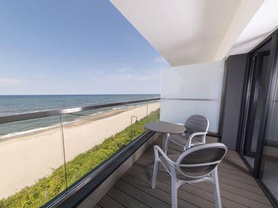 Balcone con due sedie e vista mare su una spiaggia soleggiata