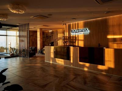 Moderna hall dell'hotel con dettagli in legno, reception e area salotto con vista sulla terrazza.