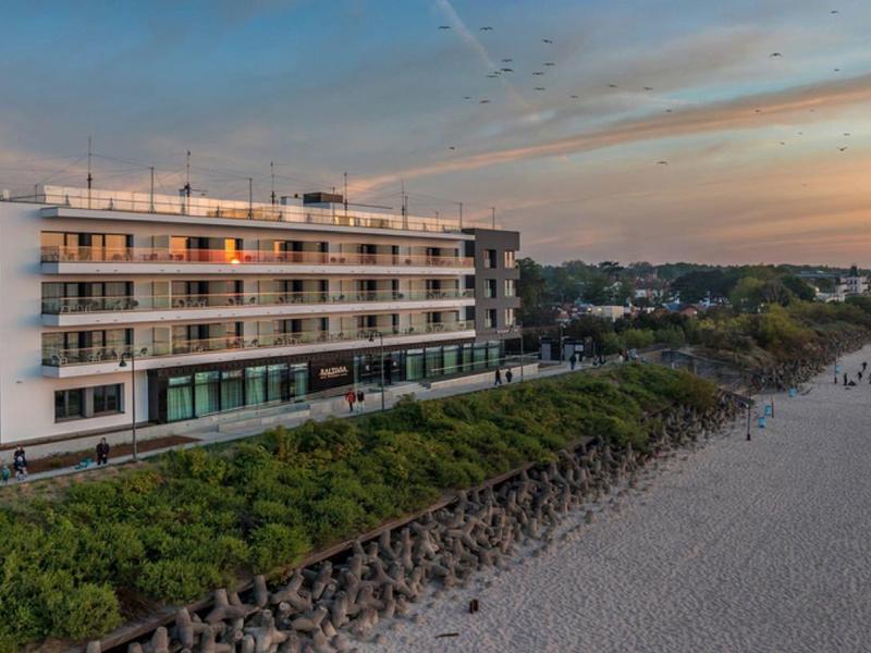 Bâtiment d'hôtel moderne sur la plage avec vue sur la mer au coucher du soleil.