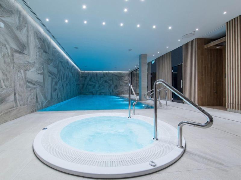 Espace bien-être moderne avec jacuzzi et piscine dans un hôtel.