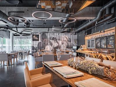 Moderně zařízená hotelová lounge s stoly, židlemi a dekorativním obrazem na stěně.