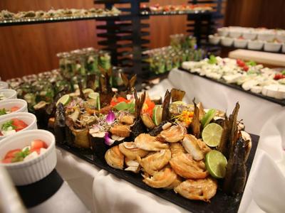 Mesa de buffet con varios platos de camarones y mariscos decorados con rodajas de lima.