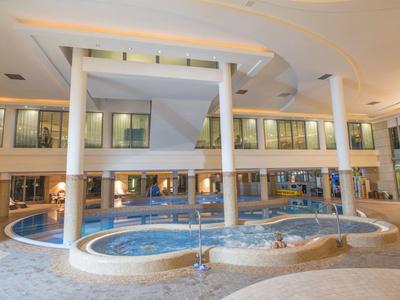 Interior de una zona de spa moderna con jacuzzi y columnas.
