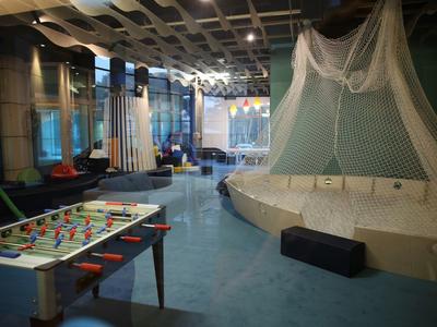 Salón moderno con futbolín, zona de asientos y red decorativa en el techo.