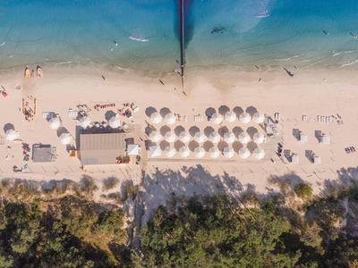 Vista aérea de una playa con sombrillas, tumbonas y agua azul clara