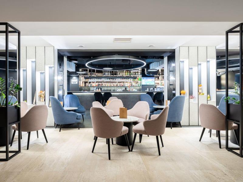 Área de bar de hotel moderna con sillones cómodos y ambiente elegante.