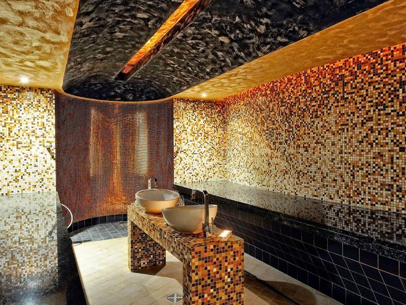 Sala de bienestar cálida con paredes de mosaico, mesa de madera y luz de velas